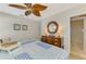 Comfortable bedroom with dresser, round mirror, ceiling fan, and open view to the tiled shower at 400 Nokomis S Ave, Venice, FL 34285