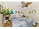 Cozy bedroom featuring a blue patterned quilt, tropical plants, and a unique leaf-shaped ceiling fan at 400 Nokomis S Ave, Venice, FL 34285