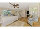 Bright main bedroom featuring wood floors, ceiling fan, a walk-in closet, and cozy seating area at 400 Nokomis S Ave, Venice, FL 34285