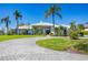 Elegant home featuring a circular driveway and lush tropical landscaping with palm trees at 4002 Las Palmas Way, Sarasota, FL 34238