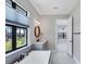 Bright bathroom with a soaking tub under a large window, light gray vanity, and open doorway at 4629 Antrim Dr, Sarasota, FL 34240