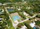 Aerial view showcasing tennis courts, a pond, and beautiful homes nestled among mature trees in a serene community at 4942 Hidden Oaks Ln, Sarasota, FL 34232