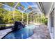 A screened-in pool area showcases a rock waterfall feature, adding to the backyard oasis ambiance at 4942 Hidden Oaks Ln, Sarasota, FL 34232