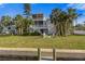 Two-story backyard home featuring a fire pit, outdoor seating, lush grass, and palm trees at 504 59Th St, Holmes Beach, FL 34217