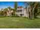 Spacious lawn with mature landscaping leading up to a two story home with screened in balconies at 504 59Th St, Holmes Beach, FL 34217