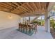 Covered patio with a six-seater table, outdoor rug, wooden beam ceiling, and natural light from surrounding landscape at 504 59Th St, Holmes Beach, FL 34217