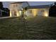 Inviting home with exterior lights, well-manicured lawn, and tidy landscaping at dusk at 5104 Silver Bell Dr, Port Charlotte, FL 33948
