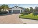 Inviting single-Gathering home featuring a brick driveway, lush landscaping, and a convenient three-car garage at 5203 Rushmere Ct, Palmetto, FL 34221