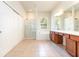 Bright bathroom featuring tile floors, a glass-enclosed shower, a soaking tub, and a double vanity with wood cabinets at 5405 98Th E Ave, Parrish, FL 34219