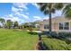 A view of the community clubhouse with a green lawn, palm trees and manicured hedges at 5405 98Th E Ave, Parrish, FL 34219