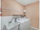 Practical laundry room with white washer, dryer, utility sink, and shelving for storage at 566 Corrientes Cir, Punta Gorda, FL 33983