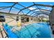 An aerial view shows a swimming pool, spa, and patio seating in a screened enclosure at 566 Corrientes Cir, Punta Gorda, FL 33983