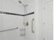 All-white bathroom has shower with safety bars and tile surround at 610 Cumberland Rd, Venice, FL 34293