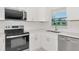 Modern kitchen features sleek appliances, white cabinetry, and a bright window overlooking the yard at 610 Cumberland Rd, Venice, FL 34293