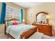 Cozy bedroom with wood furniture, neutral walls, and a bright window with blue curtains at 6320 Rosefinch Ct # 101, Lakewood Ranch, FL 34202