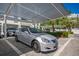 View of the covered parking featuring a silver Lexus with mature trees and buildings in the background at 635 S Orange Ave # 404, Sarasota, FL 34236