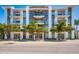 Modern building featuring a textured facade, glass balconies, and mature trees along the street at 635 S Orange Ave # 404, Sarasota, FL 34236