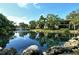 Picturesque pond featuring a fountain, rocks, and building reflection in the water at 6450 Wild Oak Bay Blvd # 240, Bradenton, FL 34210