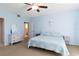 Airy bedroom with a blue comforter, white dresser, and an ensuite bathroom through an open door at 6905 Arbor Oaks Ct, Bradenton, FL 34209