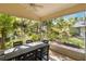 Enclosed porch with a ceiling fan, a table and a view of the green garden at 6905 Arbor Oaks Ct, Bradenton, FL 34209