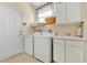 Bright laundry room with washer, dryer, utility sink, white cabinets, and tiled floor at 730 Foggy Morn Ln, Bradenton, FL 34212