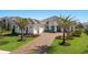 Beautiful single-story home with manicured lawn, brick driveway, and mature palm trees at 7977 Bowspirit Way, Lakewood Ranch, FL 34202
