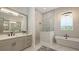 Well-lit bathroom featuring dual sinks, standalone tub, glass shower, and modern fixtures at 8348 Catamaran Cir, Lakewood Ranch, FL 34202
