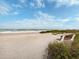 A serene beach view with a wooden bench overlooking the ocean at 8767 Midnight Pass Rd # 403F, Sarasota, FL 34242