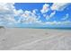 Expansive beach with white sand meeting the turquoise ocean under a partly cloudy blue sky at 8767 Midnight Pass Rd # 403F, Sarasota, FL 34242