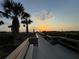 Scenic boardwalk lined with palm trees, leading to a picturesque sunset view at 8767 Midnight Pass Rd # 403F, Sarasota, FL 34242