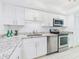 A well-lit kitchen featuring granite countertops, stainless steel appliances and white cabinetry at 8767 Midnight Pass Rd # 403F, Sarasota, FL 34242