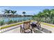 Balcony view with two chairs overlooking the waterfront and palm trees, ideal for relaxation and enjoying tropical scenery at 9122 Midnight Pass Rd # 24, Sarasota, FL 34242
