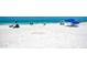 Sandy beach with scattered beachgoers, blue and colorful umbrellas, and clear turquoise water in the background at 9122 Midnight Pass Rd # 24, Sarasota, FL 34242