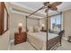Bright bedroom features a canopy bed, ceiling fan, wooden dresser, and shuttered window with neighborhood views at 9122 Midnight Pass Rd # 24, Sarasota, FL 34242
