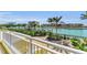 Balcony offering serene waterfront view with lush greenery, boats, and buildings against a clear sky at 9122 Midnight Pass Rd # 24, Sarasota, FL 34242