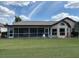 Rear exterior view featuring a screened lanai, lush backyard, and covered patio area at 4906 Peridia E Blvd, Bradenton, FL 34203
