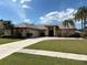 Charming single-story home with a well-manicured lawn and mature palm trees at 4906 Peridia E Blvd, Bradenton, FL 34203