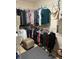 Neatly organized walk-in closet with hanging clothes, shelves, and a decorative ottoman at 4906 Peridia E Blvd, Bradenton, FL 34203