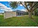 The backyard features a screened pool enclosure, lush landscaping, and a large tree for shade at 7251 Sunnybrook Blvd, Englewood, FL 34224