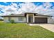 Well-maintained single-story home with a manicured lawn, dark garage door, and decorative plants at 7251 Sunnybrook Blvd, Englewood, FL 34224