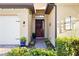 Inviting front entrance featuring a dark wood door, potted plants, brick pathway, and a white garage door at 108 Maraviya Blvd, Nokomis, FL 34275