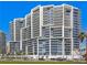 Modern condominium featuring a striking architectural design, glass balconies, and views of palm trees at 1155 N Gulfstream Ave # 708, Sarasota, FL 34236