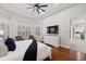 Comfortable main bedroom featuring tray ceilings, hardwood floors, and a large TV at 14817 Secret Harbor Pl, Lakewood Ranch, FL 34202