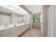 Bright bathroom featuring a long vanity with double sinks, tile flooring, and a window providing natural light at 1533 Oak Way, Sarasota, FL 34232