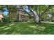 View of the well-manicured lawn, mature trees and a two-story brick home with a covered porch at 1533 Oak Way, Sarasota, FL 34232