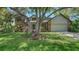 Landscaped front yard with beautiful plants and a large tree in front of a brick home with a blue front door at 1533 Oak Way, Sarasota, FL 34232