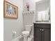 Powder room featuring a toilet, vanity, and decorative wall art and shelving at 17108 Harvest Moon Way, Bradenton, FL 34211
