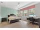 Well-lit bedroom with wood-style floors, a tray ceiling, and a dedicated workspace at 17108 Harvest Moon Way, Bradenton, FL 34211