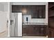 Wet bar area with stainless steel refrigerator, granite countertop, and custom dark wood cabinets at 17108 Harvest Moon Way, Bradenton, FL 34211