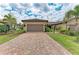 Charming home showcasing a red brick driveway, manicured lawn, and a well-maintained two-car garage at 17696 Northwood Pl, Lakewood Ranch, FL 34202